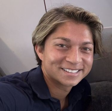 Headshot of alumnus Robbie Millwee, seeing wearing a dark-colored collared shirt