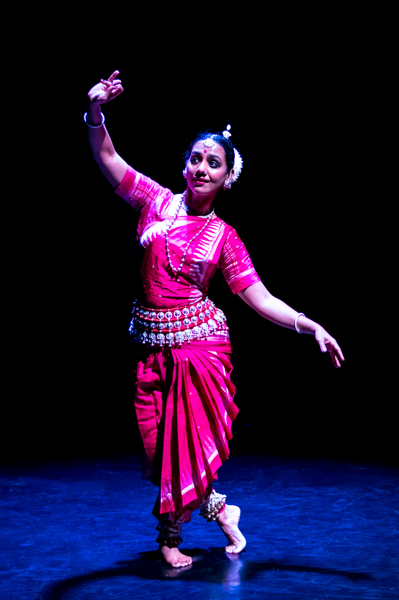 Priya Bangal dressed in a pink costume with arms extended on a stage