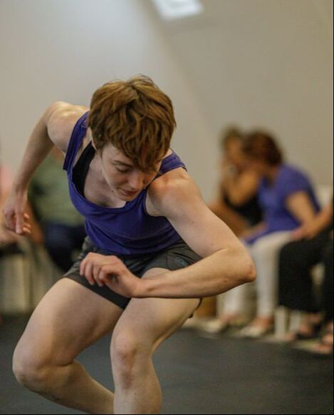 Dancer in blue bent at the waste and leaning forward