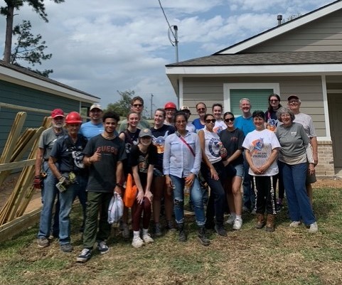 tSudent and staff volunteers standing at a house-building work site