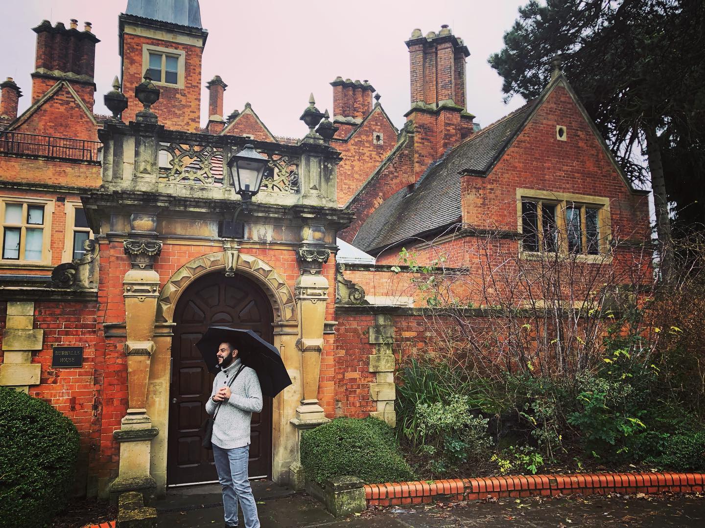 Phot of Damian Barrous-Dume with an umbrella outside of Burials House at City, London University