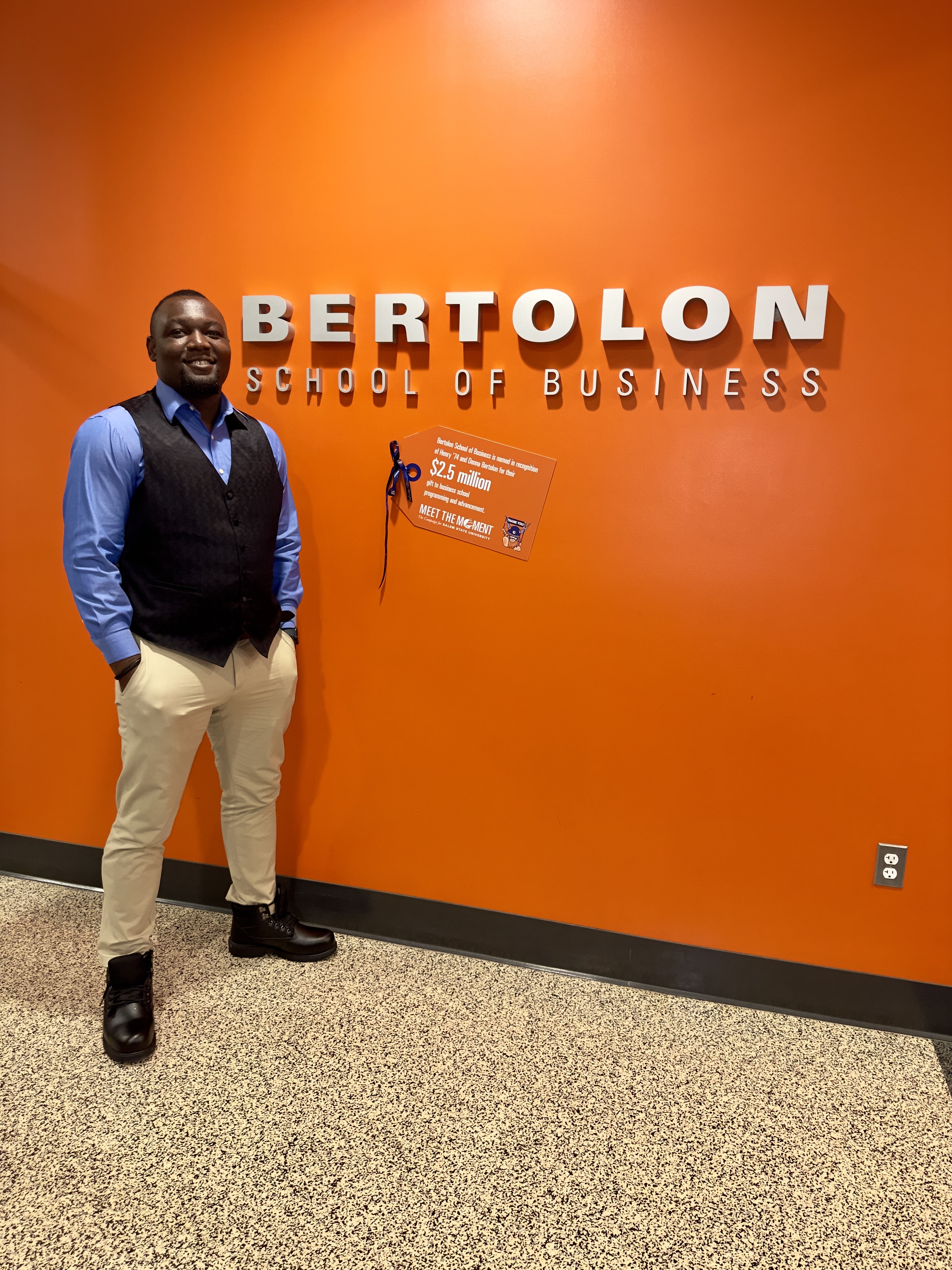 Emmanuel Ayodele stands next to the Bertolon School of Business sign