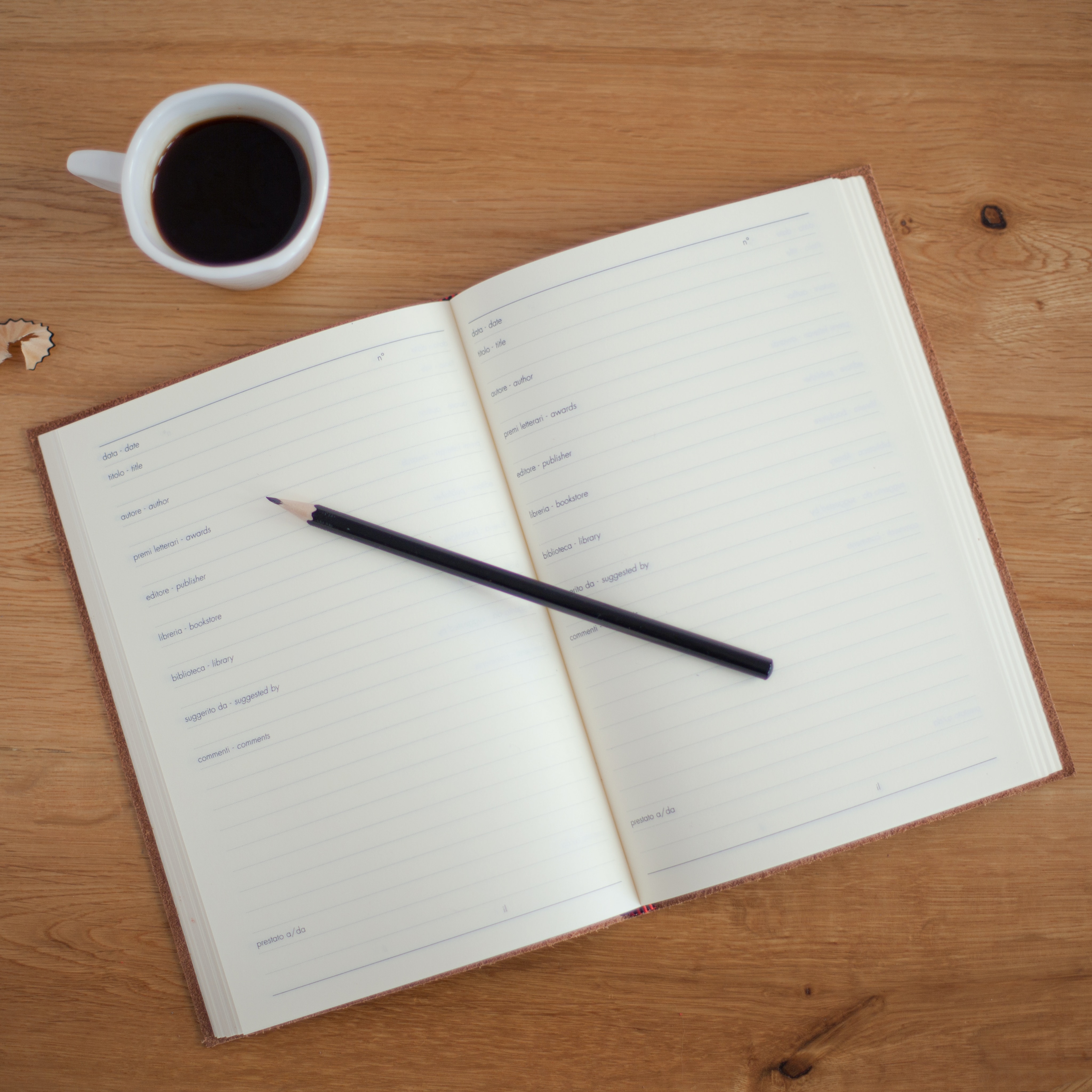 Notebook on light wood with cup of coffee on side