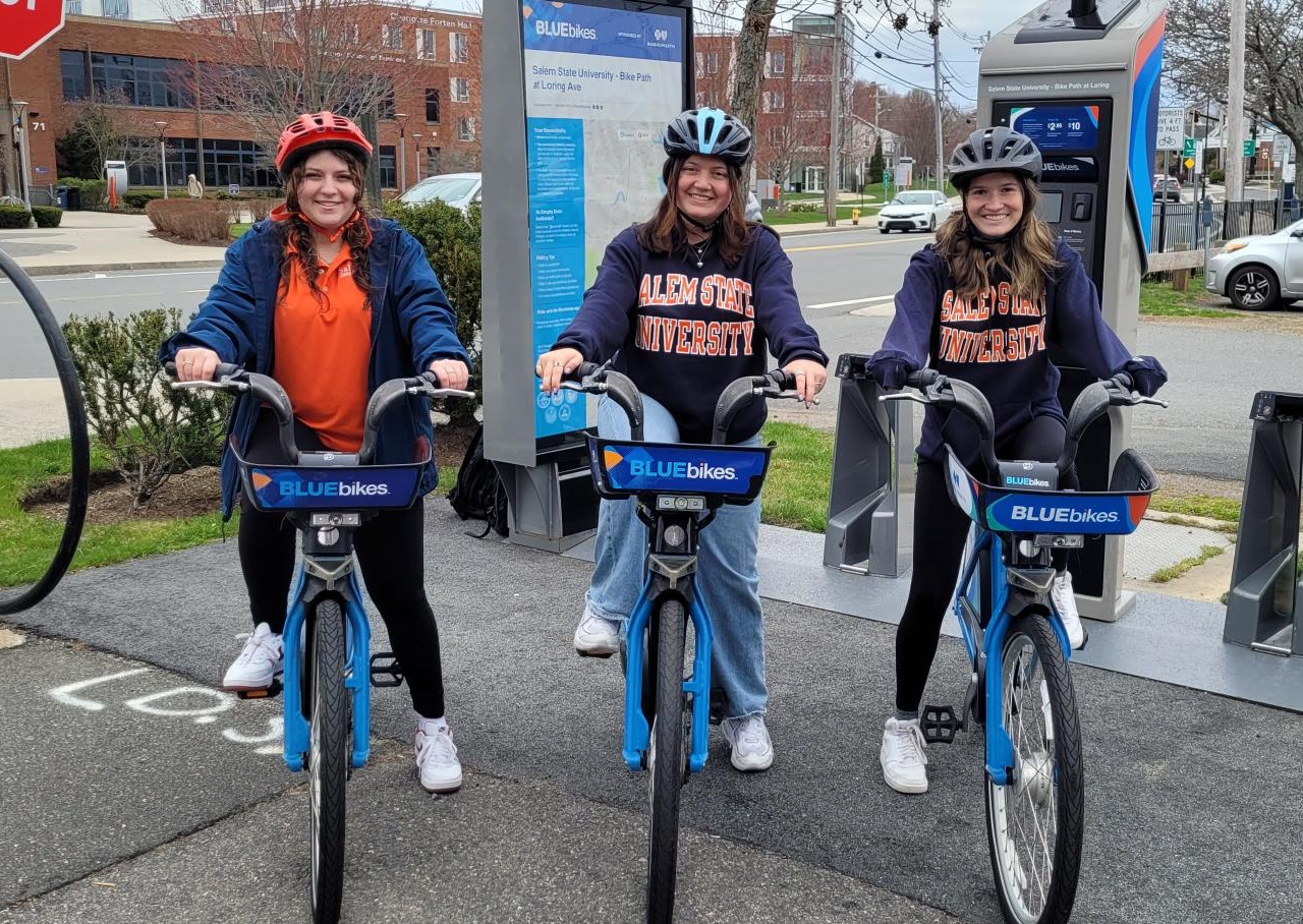 Three students ride Bluebikes on the rail trail