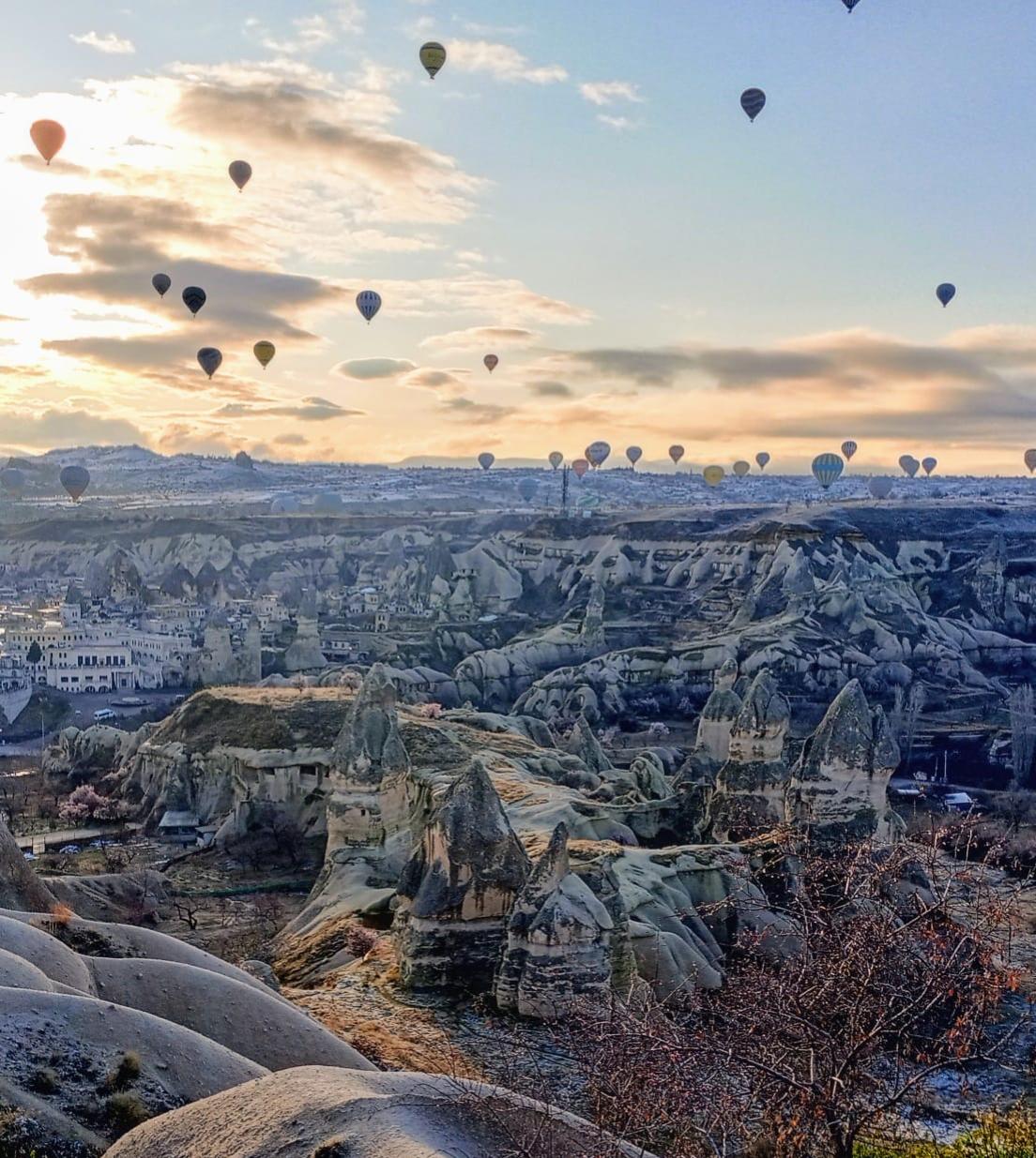 Hundreds of hot air balloons ascend at dawn over Cappadocia, Turkey. The balloons give passengers a great view of the unique rock formations and beautiful walking trails below.