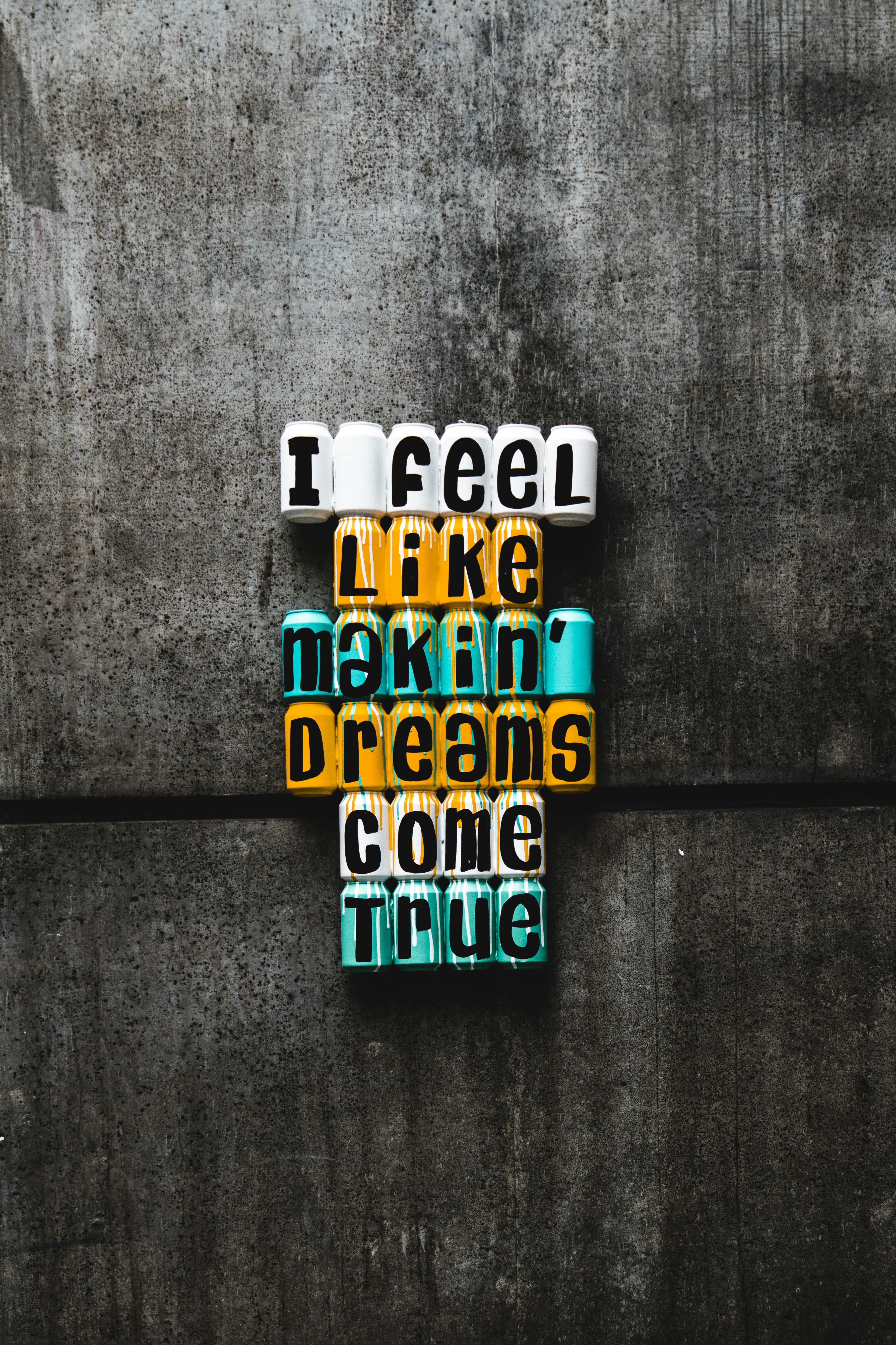 concrete wall background with the words "I feel like makin' dreams come true" in blue white and orange coloring.