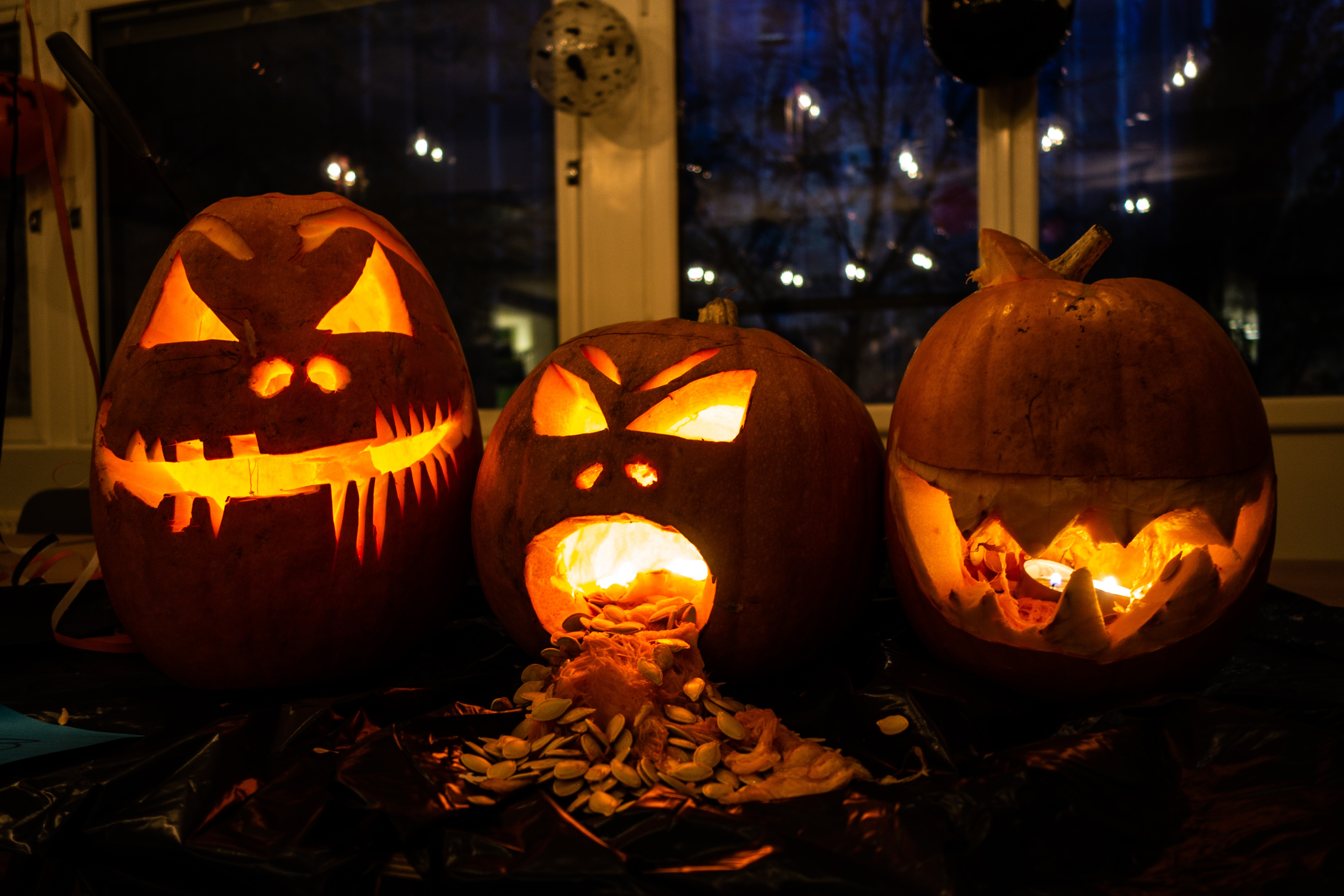 Three carved pumpkins that are lit up
