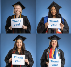 Graduates in regalia holding signs of gratefulness during commencement