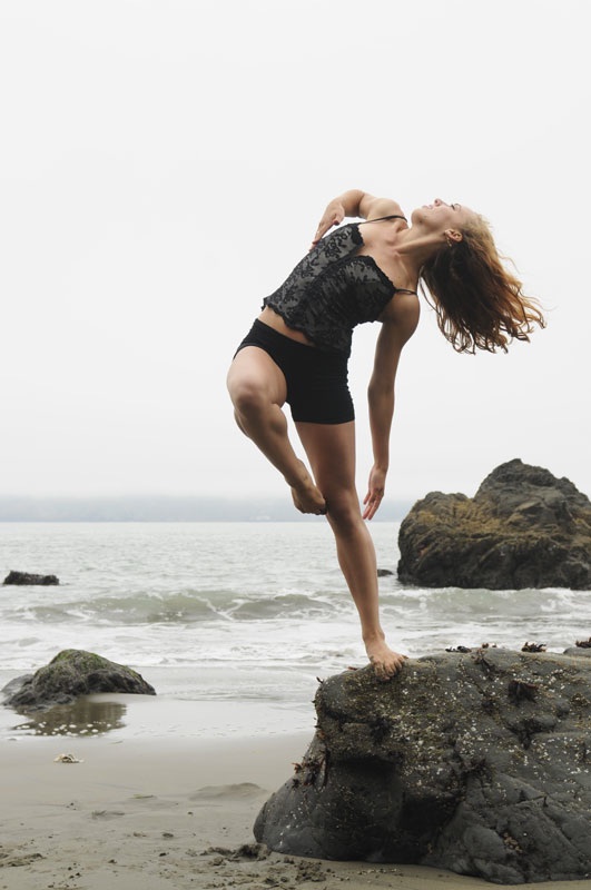 Woman dancing on a beach near rocks