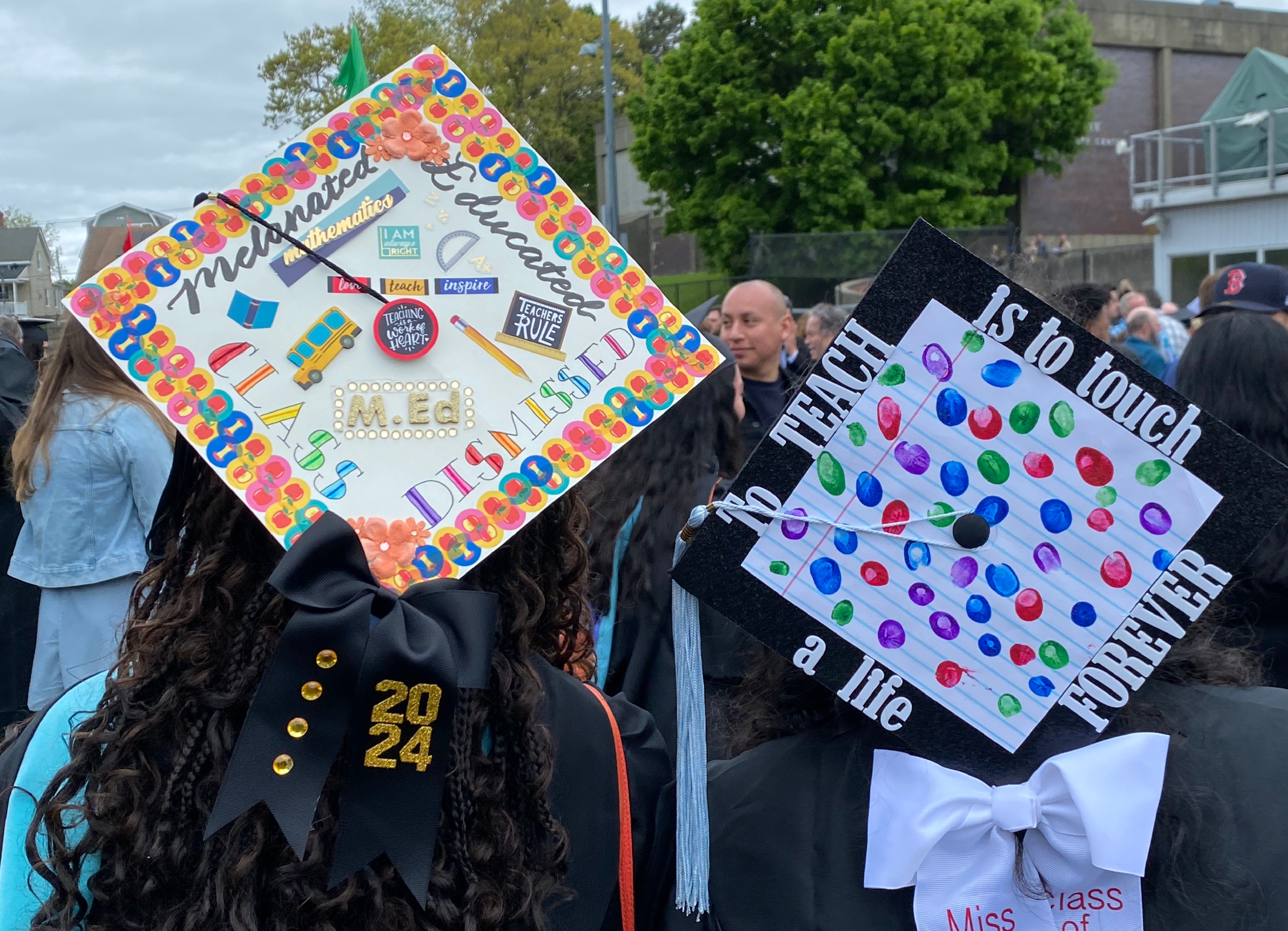 Two students from behind showing off their decorated graduation caps outside after commencement