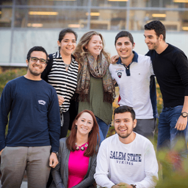 A group of seven students hanging out in front of the library in the fall