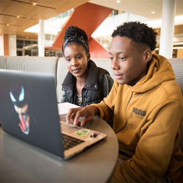 Two students study in the library during the fall