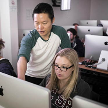 A faculty member and student at a Mac workstation