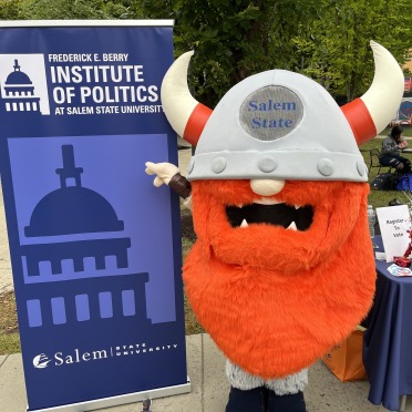 Superfan Viking mascot standing next to Berry Institute of Politics banner