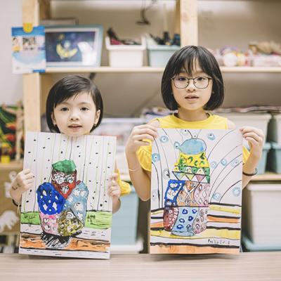 Two young children holding up their artwork