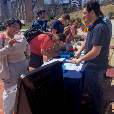 Group of students standing at a table signing petitions and talking.