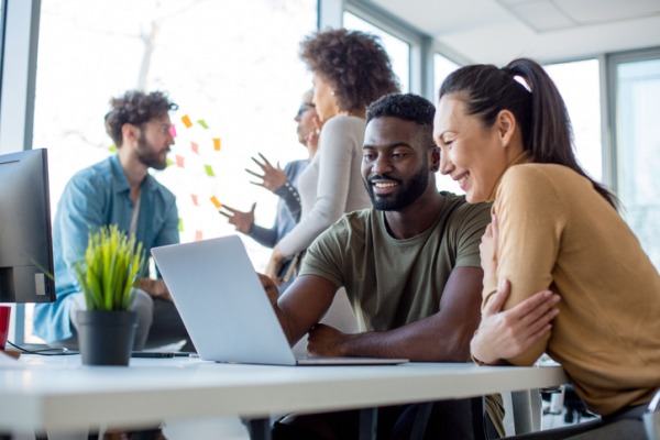 A couple sitting at a table looking at a laptop