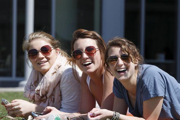 Three female students enjoy the summer weather in Salem State's North Quad