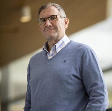 Michael Stockbridge wearing a blue sweater and looking down towards the camera